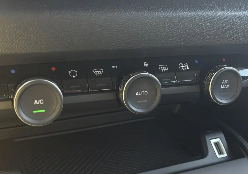 Gros plan sur les commandes de climatisation automatique de la Citroën C4 Hybrid 145 gris Mercury, avec boutons rotatifs et affichages.