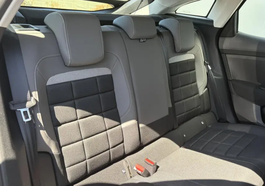 Vue intérieure des sièges arrière gris et noirs de la Citroën C4 Hybrid 2025 avec appuie-têtes et ceintures visibles.
