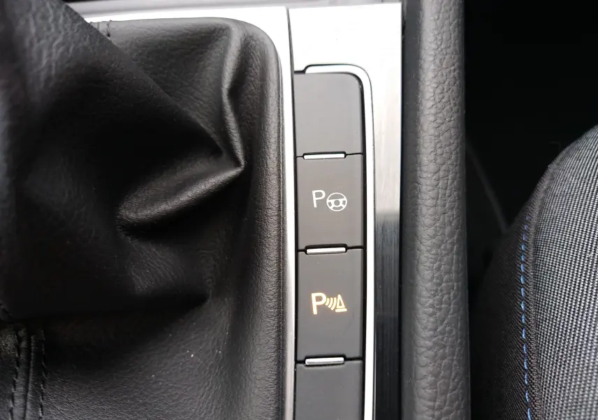 Gros plan sur les boutons de commande du système d'aide au stationnement dans une Volkswagen Golf gris reflet d'argent.