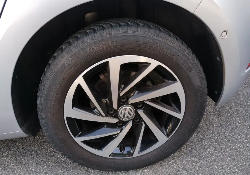 Gros plan sur la roue avant droite d’une Volkswagen Golf gris reflet d’argent avec jante alliage bicolore.