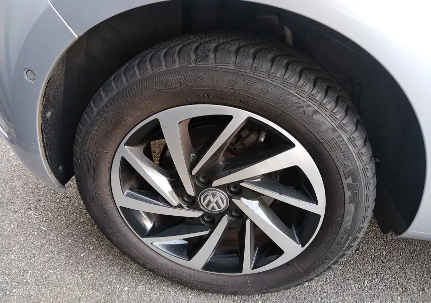 Gros plan sur la roue avant gauche d'une Volkswagen Golf gris reflet d'argent, jante alliage bicolore et pneu Goodyear.