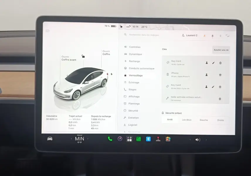 Écran tactile central affichant l'interface de contrôle d'une Tesla Model 3 blanche, vue intérieure frontale.