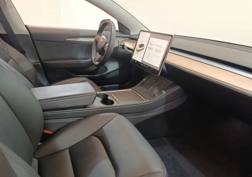 Intérieur Tesla Model 3 Grande Autonomie 2022, vue côté conducteur, sièges noirs et écran tactile central bois clair.