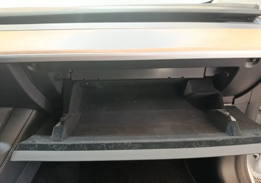 Intérieur de la Tesla Model 3 Grande Autonomie 2022, vue sur la boîte à gants ouverte avec finition bois clair au-dessus.
