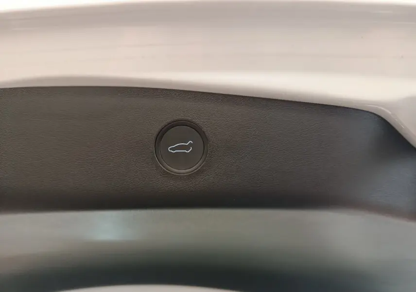 Bouton d'ouverture du coffre sur la garniture intérieure arrière d'une Tesla Model 3 blanche 2022.