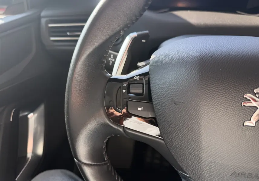 Gros plan sur le volant noir du Peugeot 308 SW 2021, montrant les commandes intégrées côté gauche.