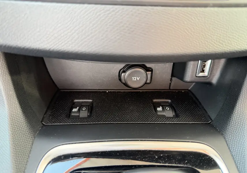 Gros plan sur les commandes de sièges chauffants et prise 12V dans l'habitacle du Peugeot 308 SW rouge rubis.