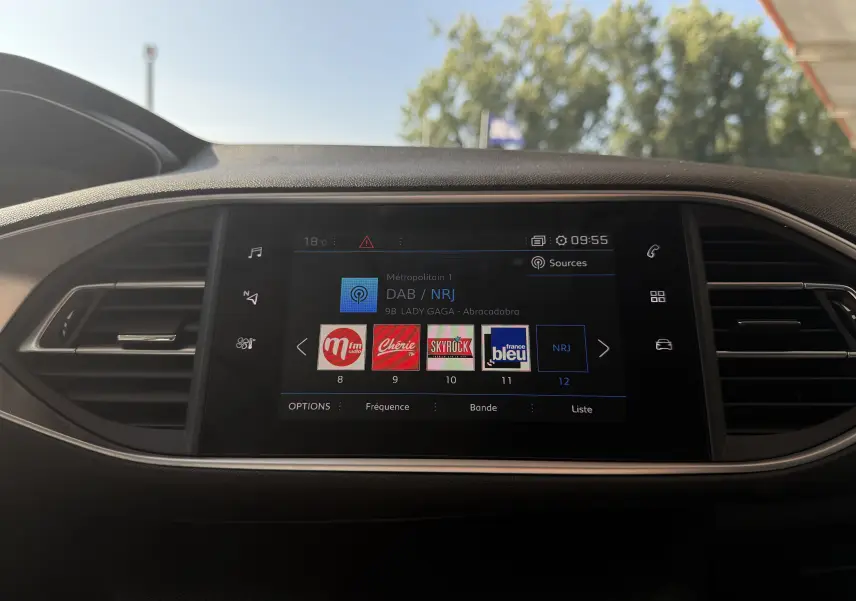Écran tactile central de la Peugeot 308 SW 2021 affichant les stations radio avec commandes autour en finition noire.