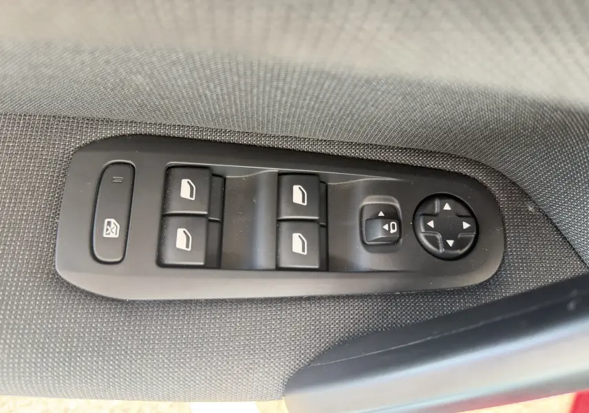 Panneau de commandes des vitres et rétroviseurs sur la porte côté conducteur d’une Peugeot 308 SW rouge rubis.