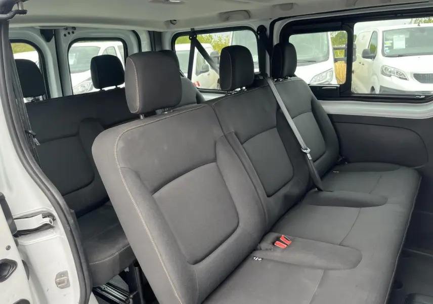 Banquette arrière noire vue côté gauche dans un Renault Trafic Fourgon blanc avec porte coulissante ouverte.