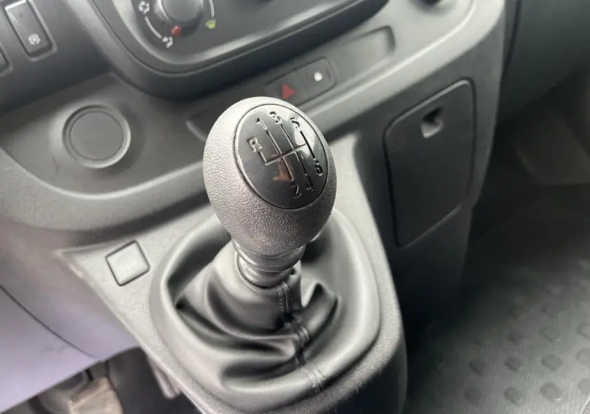 Le levier de vitesses manuel noir en gros plan dans l'habitacle du Renault Trafic Fourgon blanc de 2016.