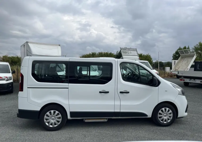 Profil côté gauche d'un Renault Trafic Fourgon blanc avec porte latérale coulissante vitrée et enjoliveurs 16 pouces.