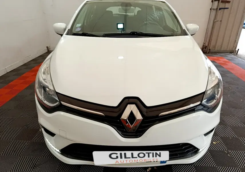 Vue frontale d'une Renault Clio Business TCe 90 blanche avec logo chromé et feux LED dans un garage.
