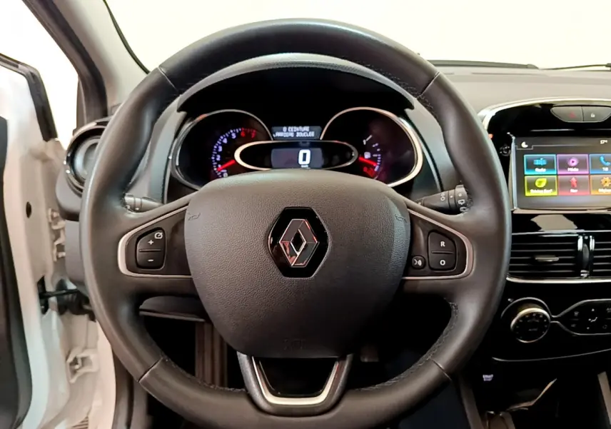 Vue intérieure centrée sur le volant cuir multifonctions d'une Renault Clio Business blanc avec tableau de bord et écran tactile.