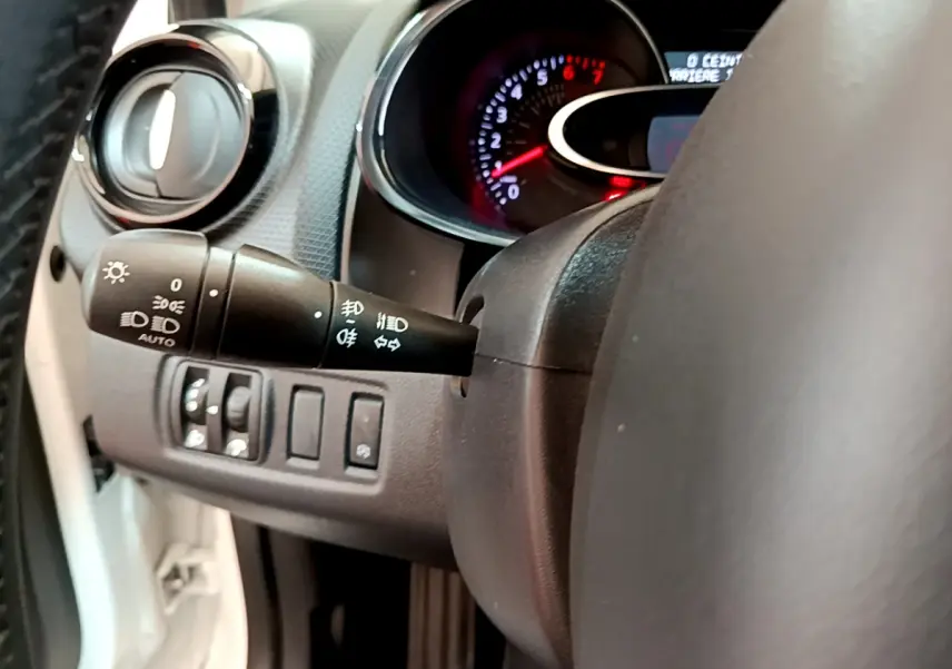 Gros plan sur la commande des phares et clignotants côté gauche du volant cuir d'une Renault Clio Business blanche de 2019.