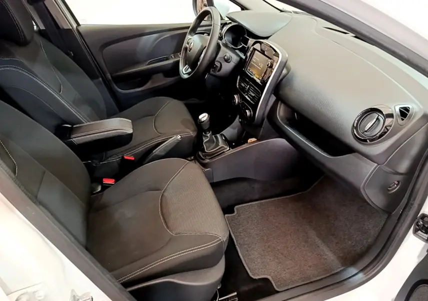 Intérieur de la Renault Clio Business blanc vue côté passager, montrant sièges noirs et tableau de bord avec écran tactile.