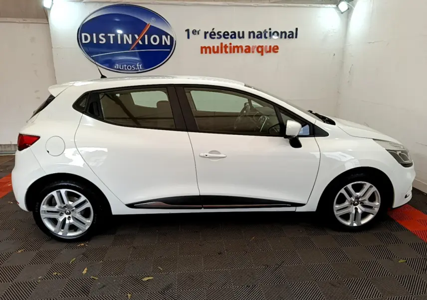 Profil latéral droit d'une Renault Clio Business TCe 90 blanche en intérieur, avec jantes alliage et poignées assorties.