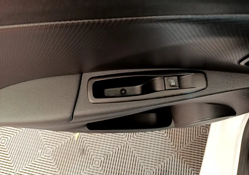 Détail de la commande de lève-vitre côté conducteur sur porte intérieure noire d'une Renault Clio Business blanche 2019.