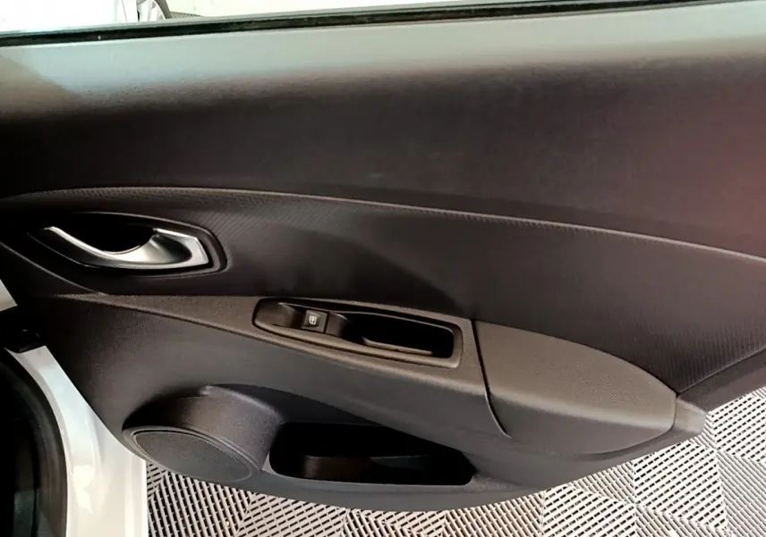 Vue rapprochée de la porte avant gauche blanche de la Renault Clio Business TCe 90 avec poignée et commande de fenêtre.