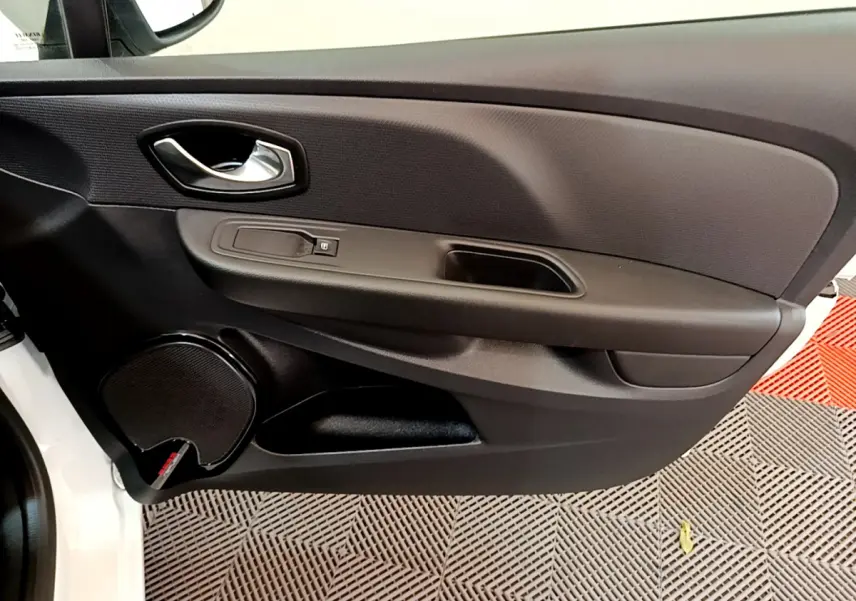 Gros plan sur la porte avant gauche noire de la Renault Clio Business blanche, avec poignée et haut-parleur intégrés.