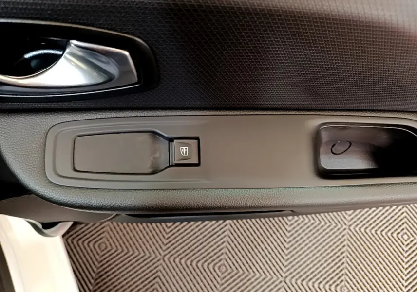 Gros plan sur la poignée intérieure et le bouton de lève-vitre côté gauche d'une Renault Clio Business blanche.