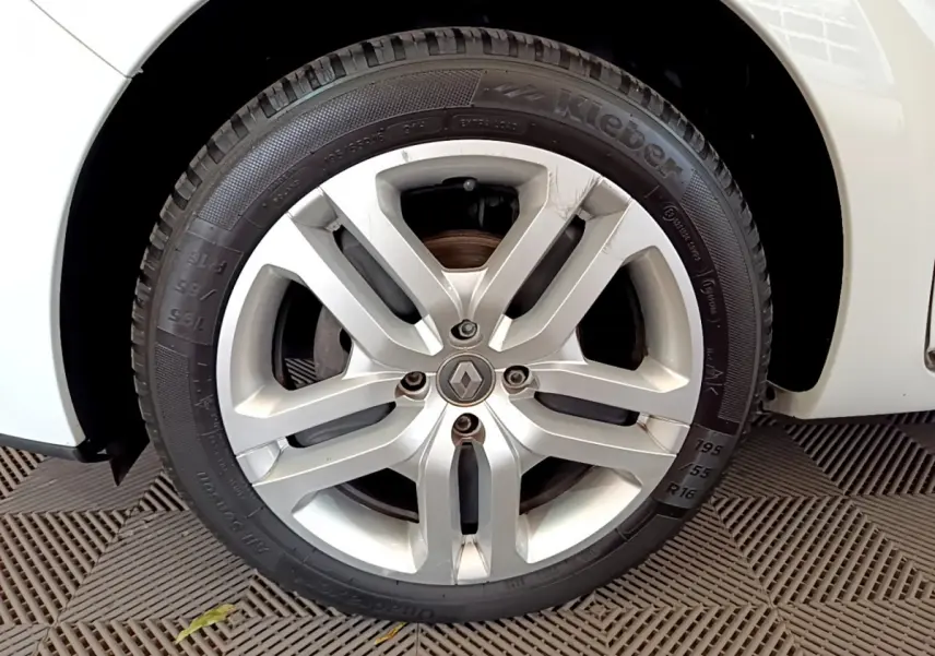 Gros plan sur la roue avant droite d'une Renault Clio Business blanche, jante alliage argentée avec logo Renault central.