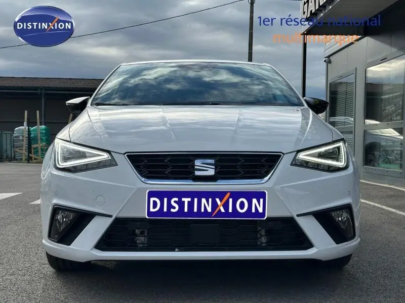 Vue frontale d'une SEAT Ibiza 1.0 TSI 115cv FR blanche Nevada métal avec phares LED anguleux allumés.
