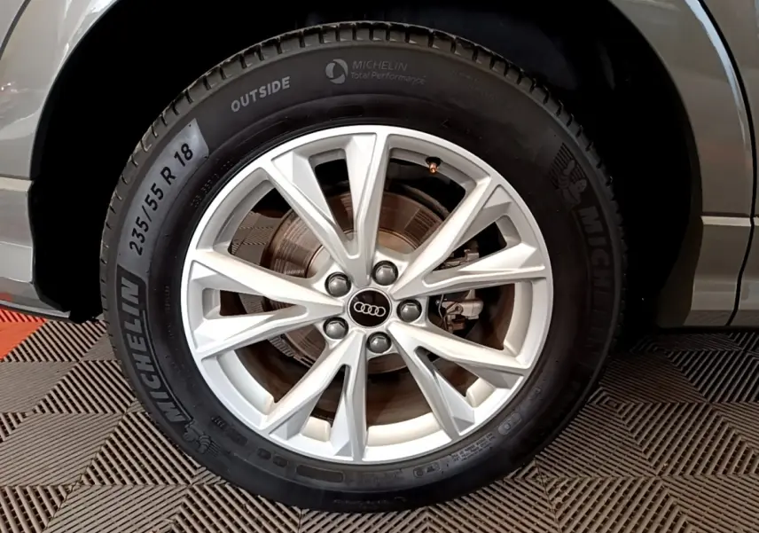 Gros plan sur la roue avant droite d’un Audi Q3 gris foncé, avec jante alliage argent et pneu Michelin.