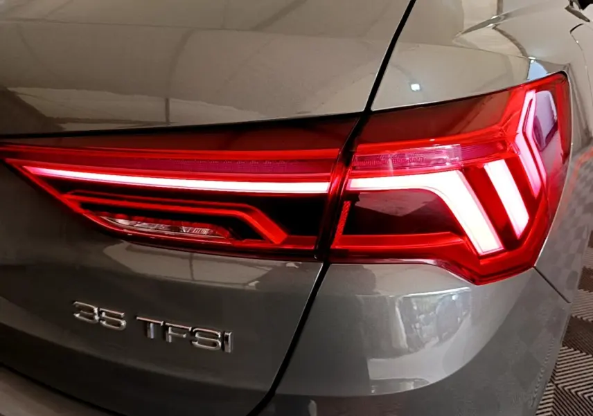 Gros plan sur le feu arrière droit rouge et la carrosserie gris foncé de l'Audi Q3 35 TFSI 2021.