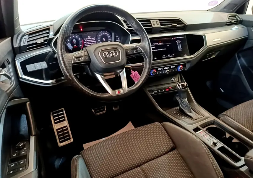 Vue intérieure côté conducteur de l'Audi Q3 35 TFSI S Line 2021, volant cuir multifonctions et tableau de bord digital.