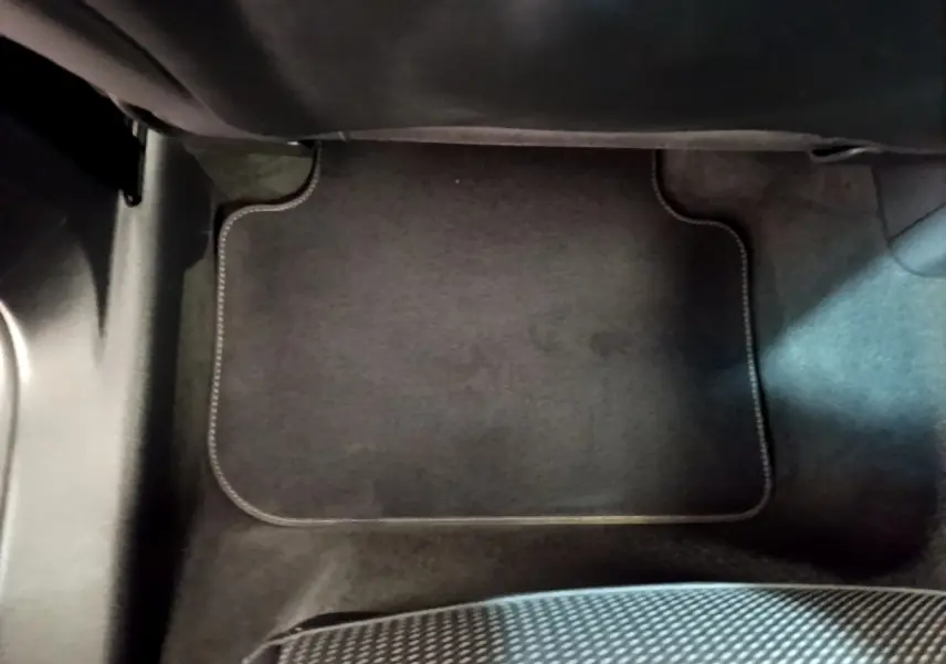 Tapis de sol noir côté passager avant dans un Audi Q3 gris foncé, vue rapprochée de l'intérieur.