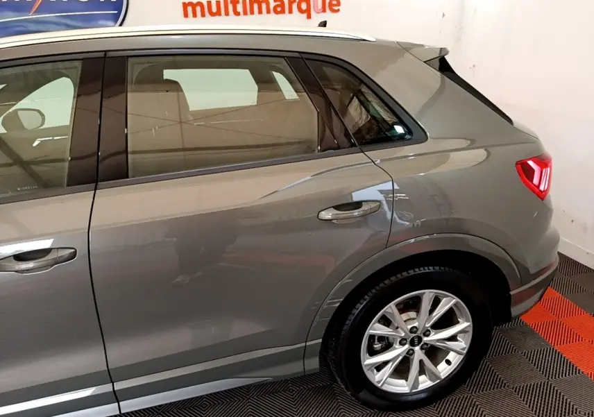 Vue latérale droite sur l'arrière d'un Audi Q3 gris foncé avec jantes alliage et feux arrière LED allumés.