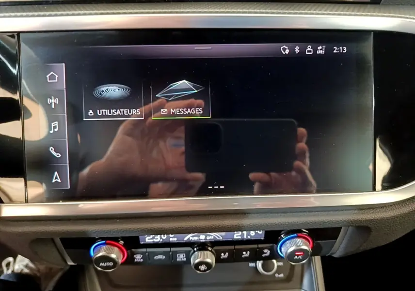 Écran tactile central et commandes climatisation du tableau de bord de l'Audi Q3 gris foncé, vue intérieure frontale.