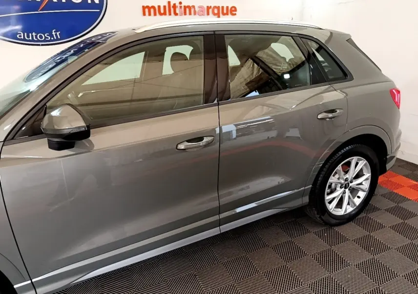 Vue latérale côté gauche d'un Audi Q3 gris foncé 35 TFSI 150 MHEV S Line avec jantes alliage et rétroviseurs assortis.