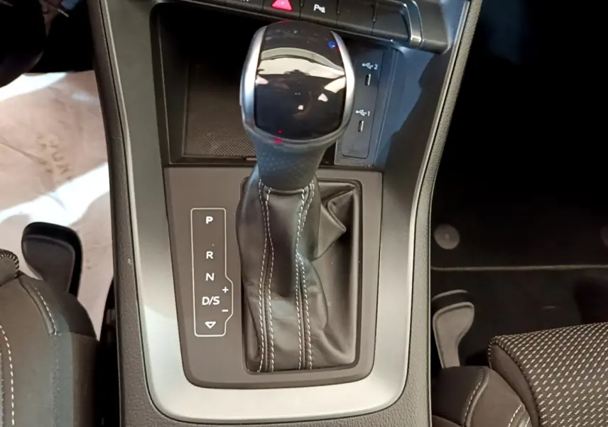 Gros plan sur la commande de la boîte automatique cuir noir avec surpiqûres blanches dans l’Audi Q3 gris foncé.