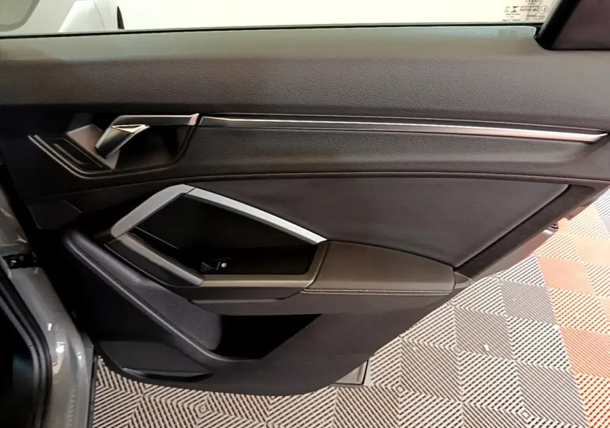 Vue rapprochée de la porte avant gauche gris foncé d’un Audi Q3 35 TFSI S Line avec poignée et garniture noire.