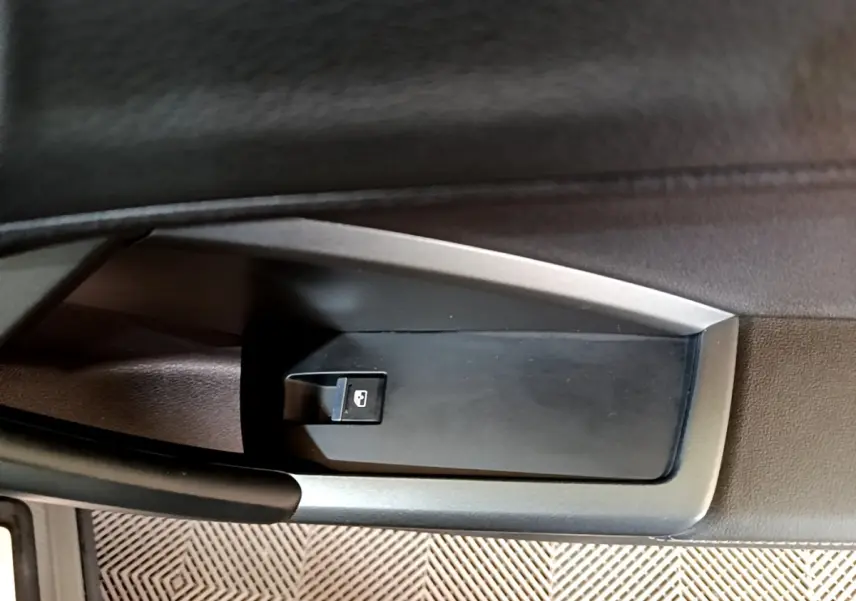 Gros plan sur le bouton de verrouillage centralisé dans la porte côté conducteur de l'Audi Q3 gris foncé 35 TFSI S line.