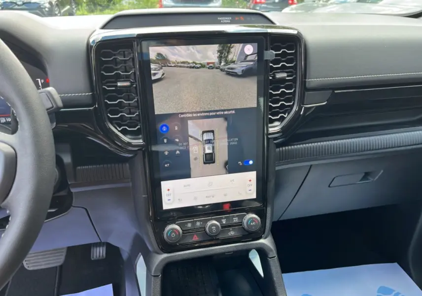 Vue intérieure du tableau de bord du Ford Ranger 2.3 PHEV avec écran tactile vertical affichant la caméra 360° et commandes climatisation.