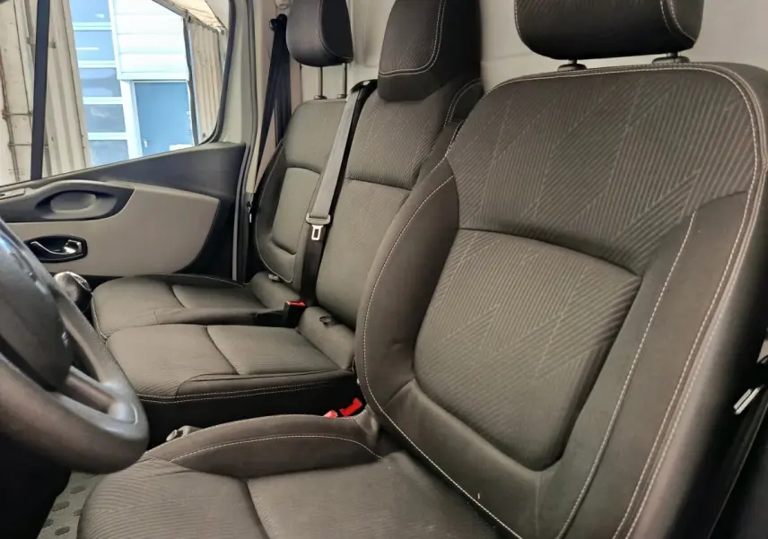 Vue intérieure côté conducteur du Renault Trafic Fourgon 2017, sièges tissu gris foncé avec ceinture de sécurité.