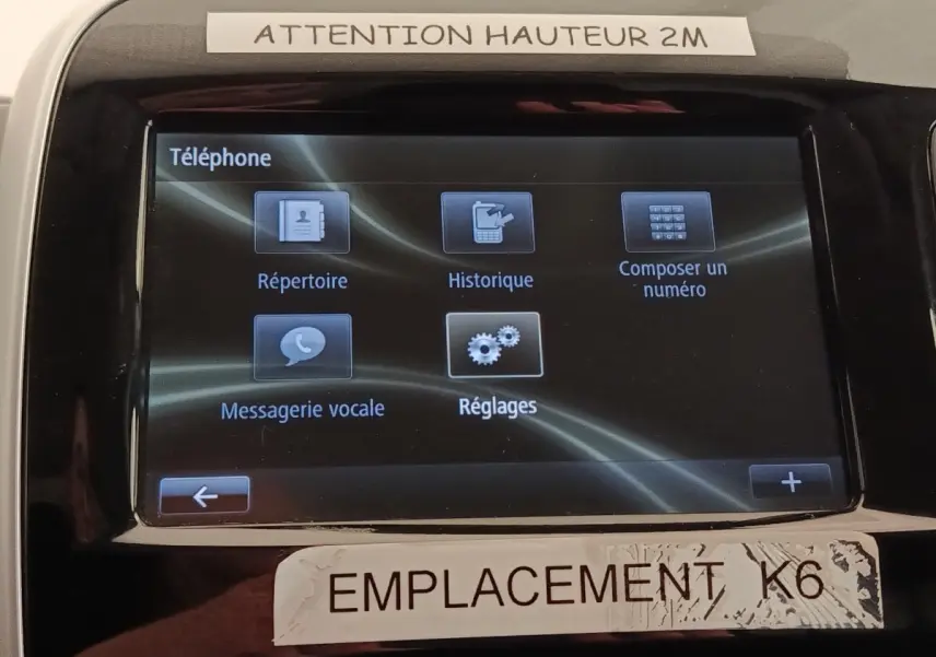 Écran tactile central du Renault Trafic Fourgon blanc, affichant le menu téléphone avec options de répertoire et réglages.