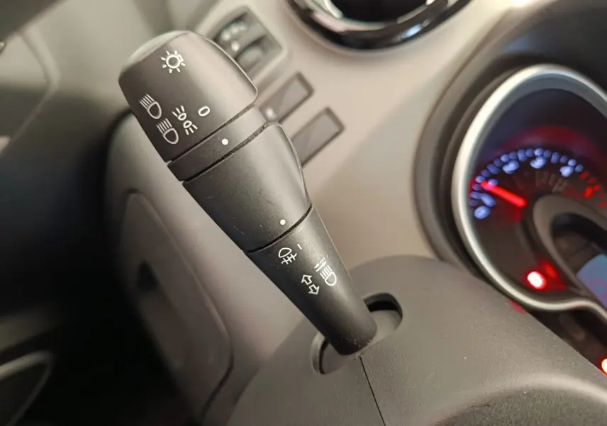 Gros plan sur la commande des phares et clignotants du tableau de bord intérieur du Renault Trafic blanc de 2017.
