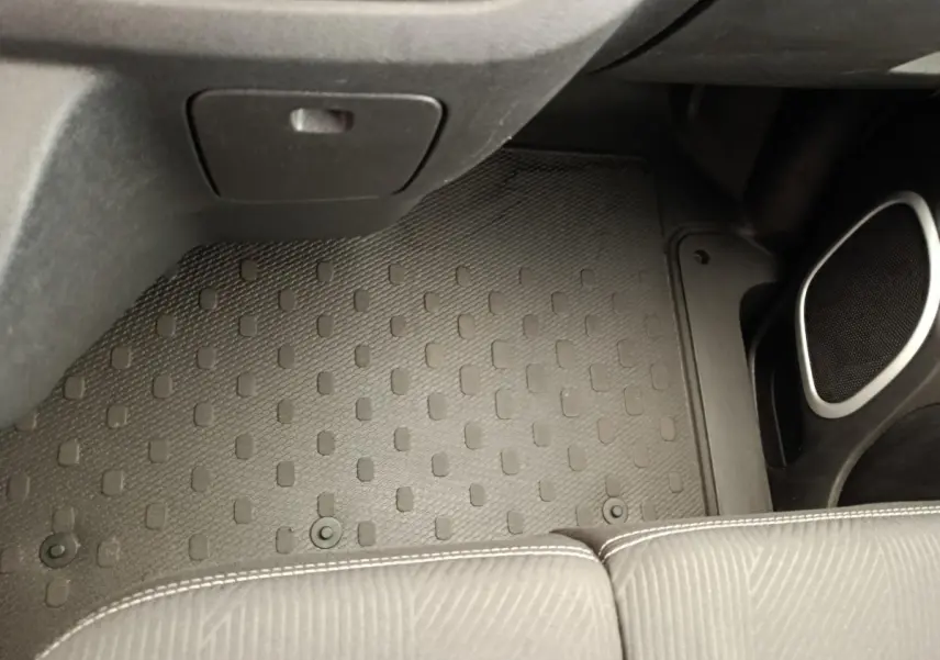 Vue intérieure du plancher côté passager avant avec tapis caoutchouc noir et partie inférieure de siège gris du Renault Trafic Fourgon blanc.