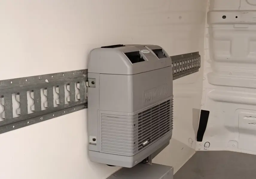 Détail intérieur montrant le système de climatisation Autoclima fixé sur la paroi blanche du Renault Trafic Fourgon blanc.