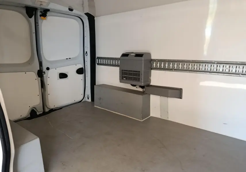 Intérieur du fourgon Renault Trafic blanc, vue arrière droite montrant l'espace de chargement vide avec cloison pleine.