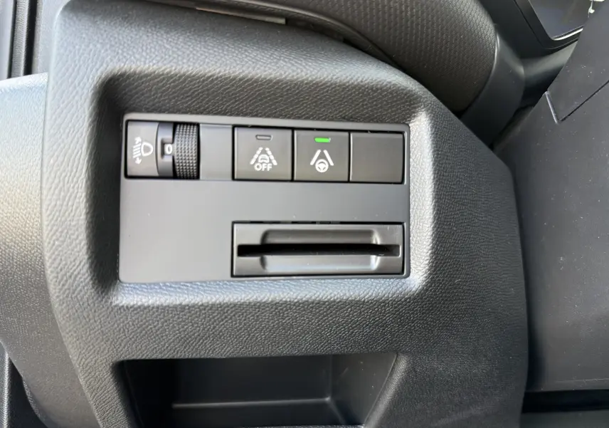 Vue rapprochée des commandes de réglage d’éclairage et d’assistance au conducteur sur le tableau de bord noir du Citroën C5 Aircross Hybrid 2025.