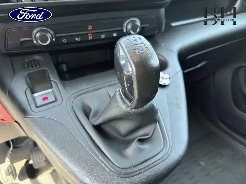 Le levier de vitesses manuel en gros plan dans l'habitacle d'un Peugeot Partner blanc, avec commandes de climatisation visibles.