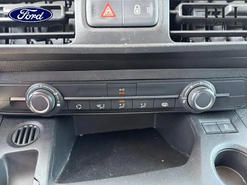 Tableau de bord noir du Peugeot Partner blanc 2019, vue centrée sur les commandes de climatisation manuelle.