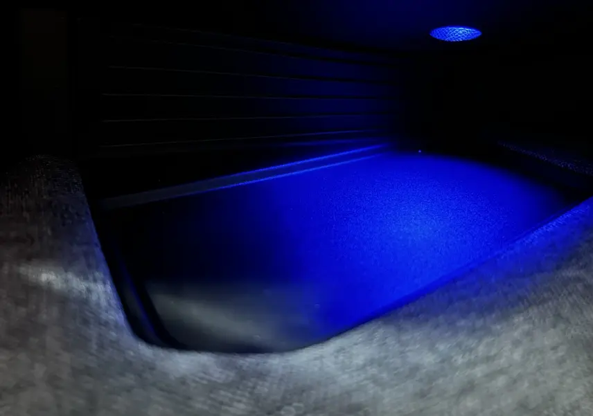 Gros plan sur l'éclairage d'ambiance bleu dans le compartiment de rangement intérieur du Peugeot 3008 III Hybrid blanc.