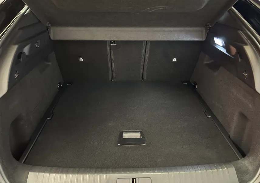 Coffre ouvert vu de l'arrière d'un Peugeot 3008 blanc, montrant un espace de chargement propre et éclairé.