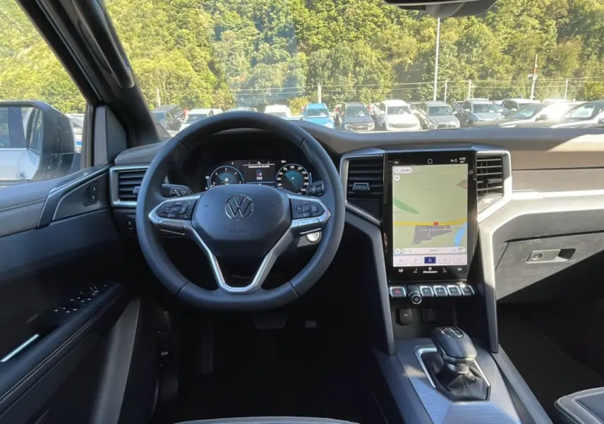 Vue intérieure du tableau de bord du Volkswagen Amarok Simple Cabine blanc 2025, avec volant multifonction et écran tactile vertical.
